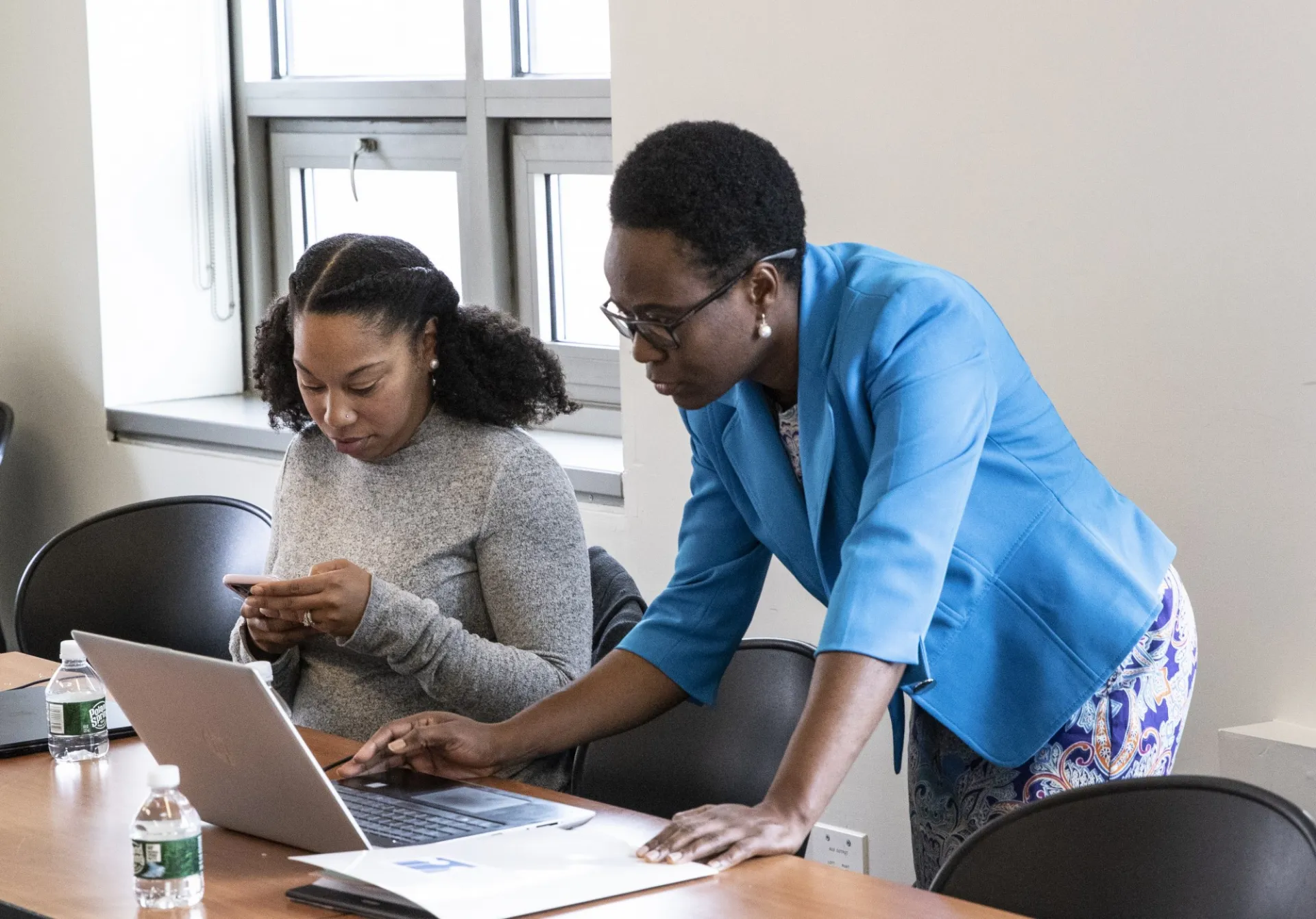 a scholars bent over a laptop working next to another scholar